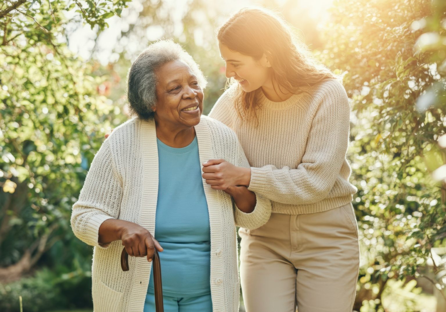 Volunteer is accompanying a smiling senior woman holding a cane in a garden
